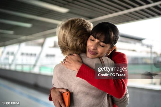 enkelin verlässt und umarmt die enkelin in einer u-bahn-station oder einem flughafen - generationsunterschied stock-fotos und bilder