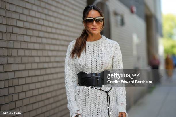 Tamara Kalinic wears beige sunglasses from Saint Laurent, gold Clash earrings from Cartier, a pale gray wool braided long sleeves / slit long dress,...