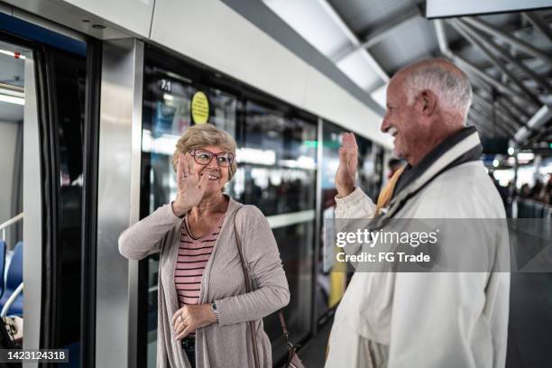 senior couple waving goodbye on the subway platform - older couple waving goodbye stock pictures, royalty-free photos & images