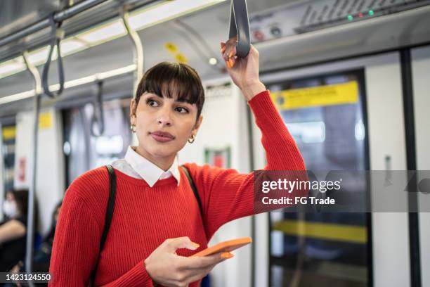mujer joven usando el teléfono móvil en el tren subterráneo - vagón fotografías e imágenes de stock