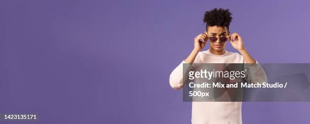 portrait of sassy and confident young judgemental man,taking-off - sassy shades foto e immagini stock