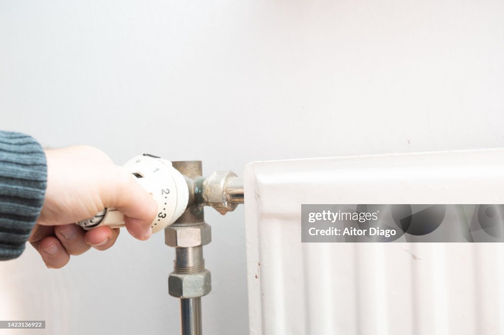 View of person adjusting the temperature of a radiator. Energy prices has increased a lot.