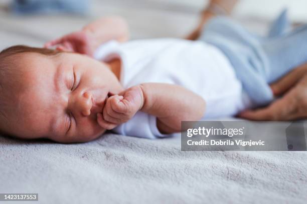 自宅で眠っている新生児 - 指をくわえる ストックフォトと画像