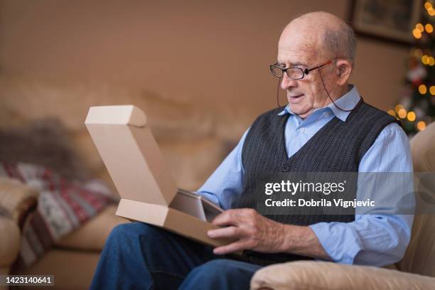 old man opening christmas present at home - elderly receiving paperwork stock pictures, royalty-free photos & images