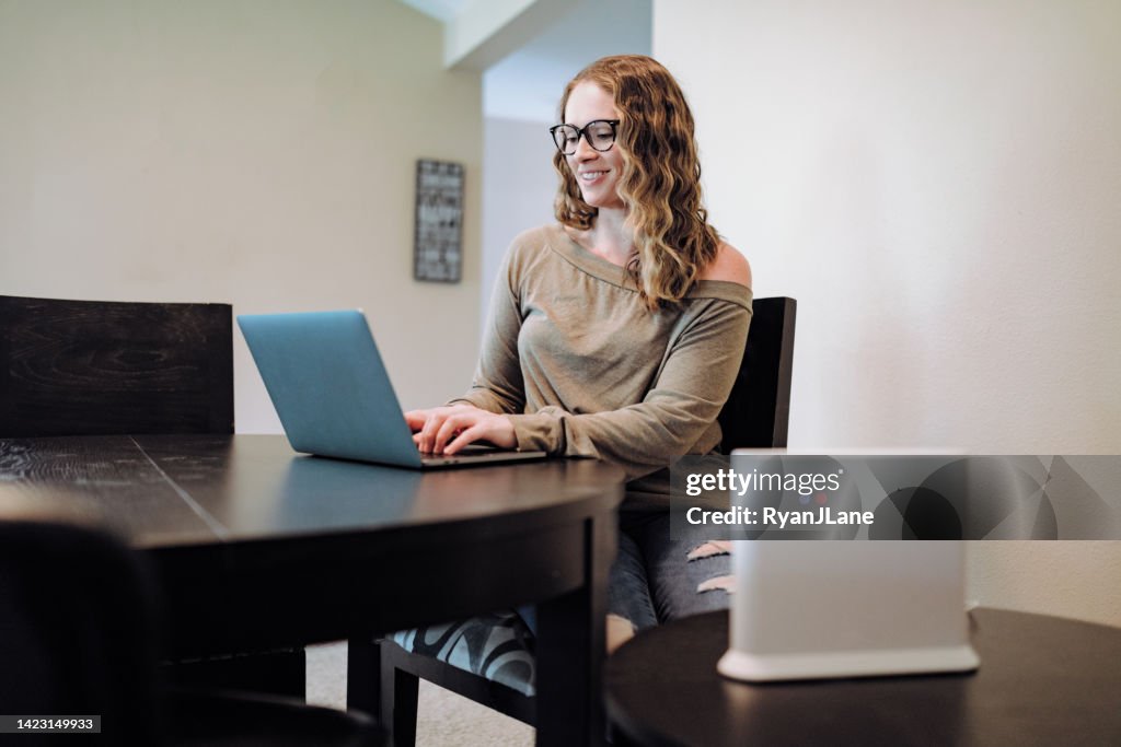 Mulher usando laptop na sala de jantar do apartamento