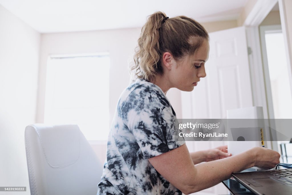 Woman Connecting Router In Home Office