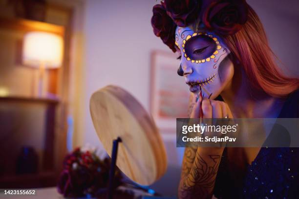 young woman doing make-up for day of the dead celebration - sugar skull stock pictures, royalty-free photos & images