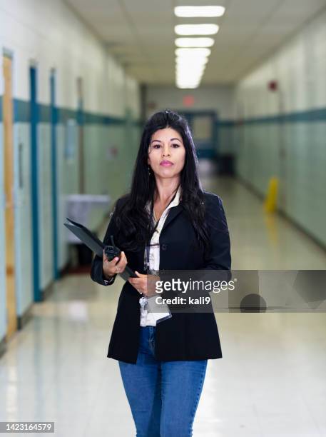 hispanic teacher or principal in school hallway - teacher with folder stock pictures, royalty-free photos & images