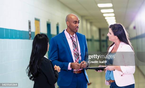 multiracial group of teachers meet in school hallway - teacher with folder stock pictures, royalty-free photos & images