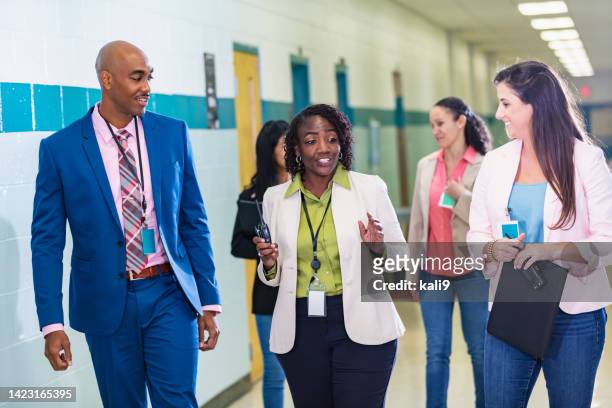 multiracial group of teachers walking in school hallway - teacher stock pictures, royalty-free photos & images