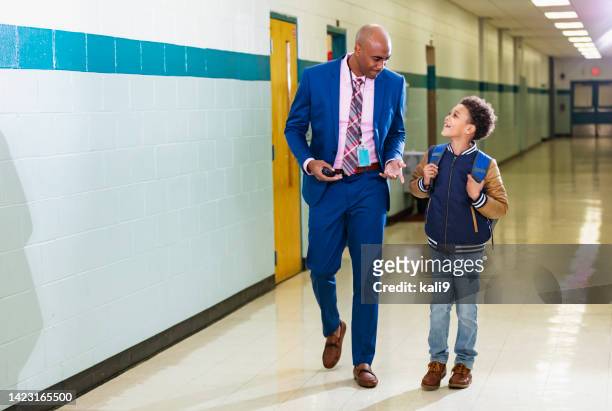 elementary student walking with teacher in school hallway - school principal stock pictures, royalty-free photos & images