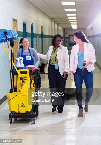 Teachers and janitor walking thru school corridor