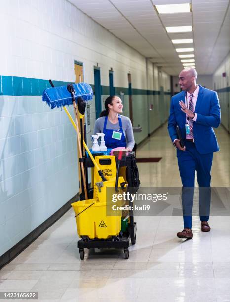 teacher walks through school hallway, waves to custodian - curador imagens e fotografias de stock