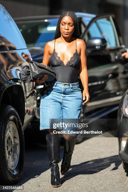 Guest wears a black lace print pattern v-neck tank-top, a black shiny leather grained handbag from Chanel, blue denim large shorts, black shiny...