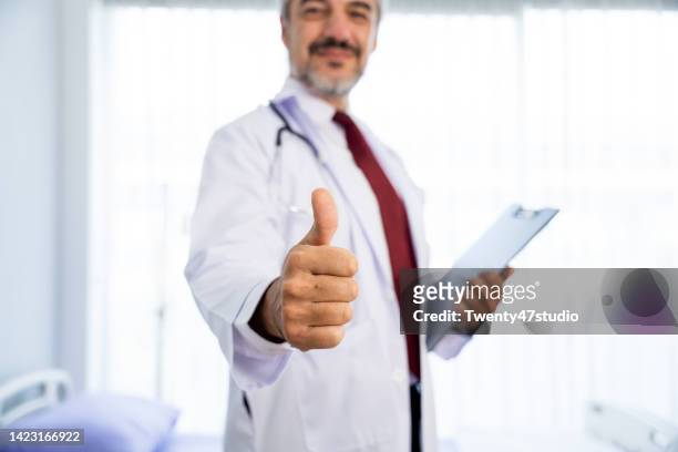 close up doctor in lab coat giving thumb up - doctor lab coat stock-fotos und bilder