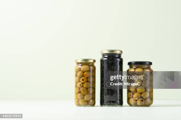 a variety of olives sealed and preserved in glass jars - black olive stockfoto's en -beelden