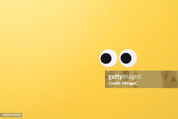 googly eyes made of paper looking to the left, copy space - comic augen stock-fotos und bilder