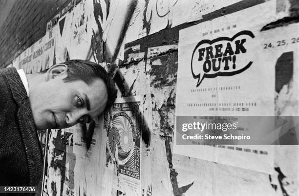 Portrait of American film director and actor Robert Downey Sr as he leans with is head on a graffiti- and advertising-covered wall, New York, New...