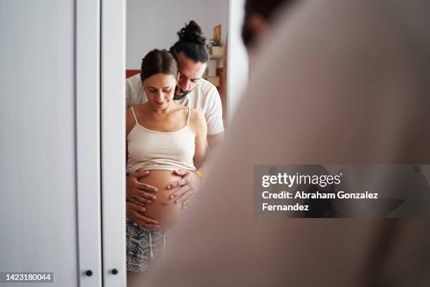 pregnant woman and her partner embracing. - happy wife stock pictures, royalty-free photos & images