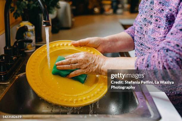 senior woman washing dishes - brillos stockfoto's en -beelden