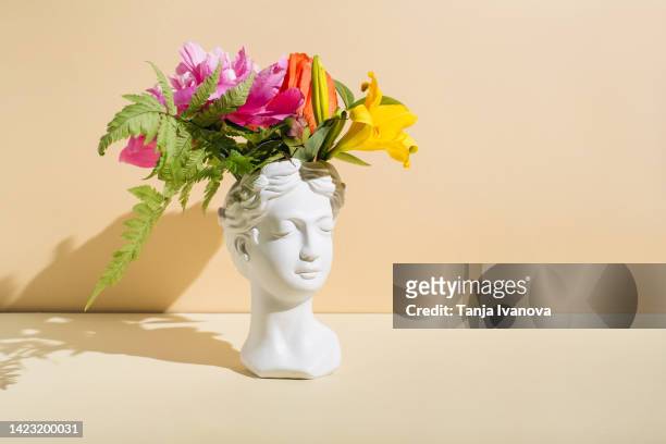retro head sculpture with flowers on beige background. creative positive thinking concept. minimal mental health awareness month. psychology, emotional wellness, progress, flowering, work on yourself idea - contemplation concept 個照片及圖片檔
