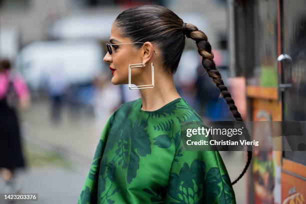 Thassia Naves with pigtail wearing green jacket with belt and pants, earrings, sunglasse outside Carolina Herrera on September 12, 2022 in New York...