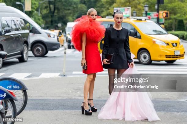 Leonie Hanne wearing red dress & Mary Leest wearing black dress, tights, pink robe wearing outside Carolina Herrera on September 12, 2022 in New York...