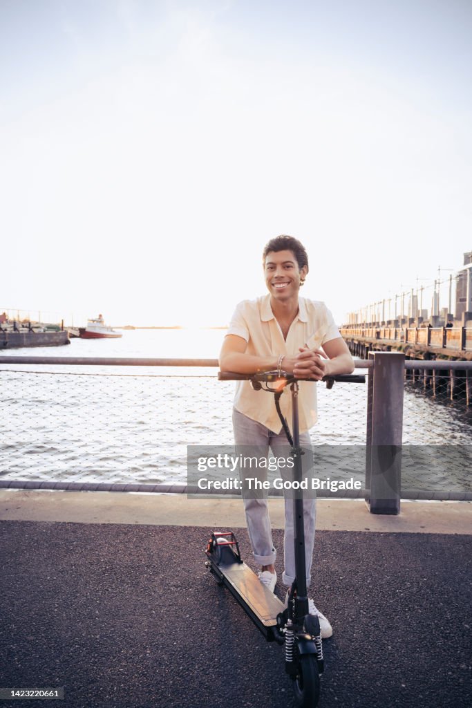 Portrait of cheerful man standing on electric scooter
