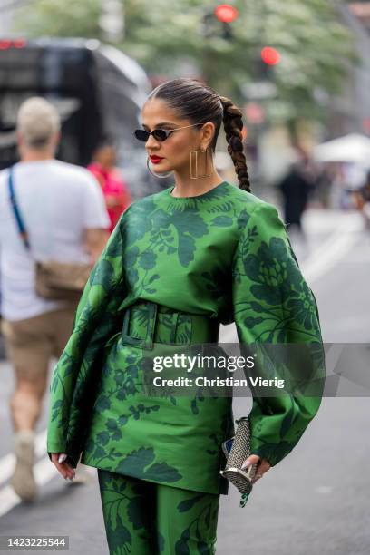 Thassia Naves with pigtail wearing green jacket with belt and pants, earrings, sunglasse outside Carolina Herrera on September 12, 2022 in New York...