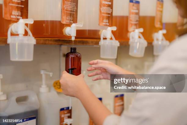 contenitore di riempimento della donna con prodotto per la pulizia nel negozio di alimentari senza plastica. - prodotto per le pulizie foto e immagini stock