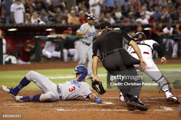 Chris Taylor of the Los Angeles Dodgers slides into home plate past catcher Carson Kelly of the Arizona Diamondbacks during the seventh inning of the...