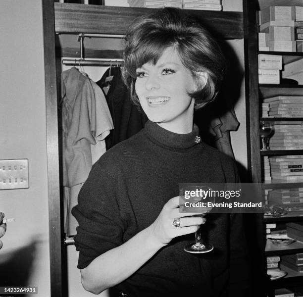 British fashion model Paulene Stone wearing a black turtleneck sweater as she holds a wineglass, United Kingdom,