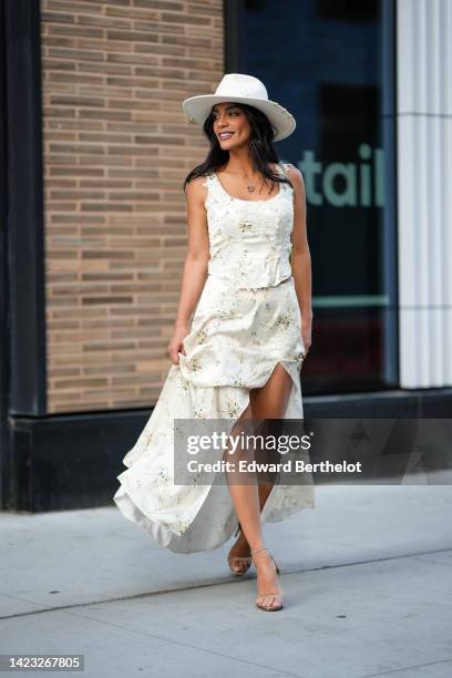 Guest wears a white felt hat, a white with green print pattern ruffled V-neck / tank-top long dress, beige strappy leather heels sandals , outside...