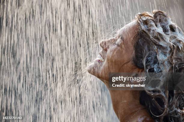 glückliche frau mit shampoo im haar unter fallendem wasser. - haare waschen stock-fotos und bilder