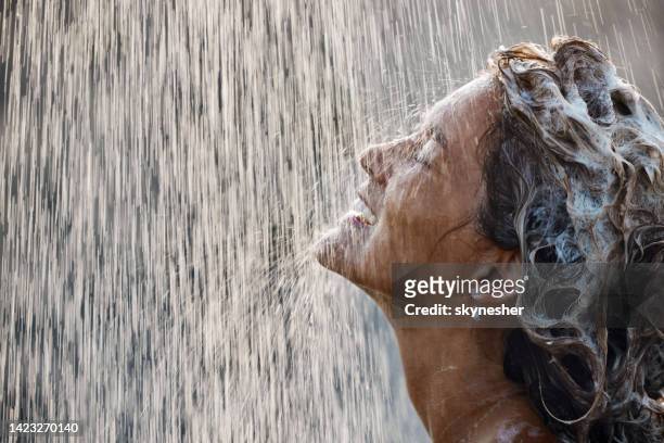 happy woman with shampoo in her hair under falling water. - washing hair stock pictures, royalty-free photos & images