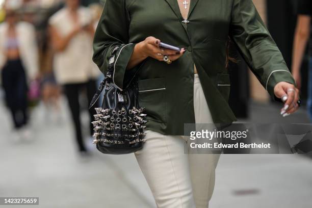 Guest wears a khaki silk with white latte borders shirt from Vivienne Westwood, a black shiny leather nailed / studded handbag from Givenchy, gold...