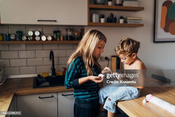 eine millennial-frau hilft ihrem sohn, windpocken loszuwerden. sie trägt medikamente auf ihn auf, die seinen juckreiz und seine rötung reduzieren - chickenpox stock-fotos und bilder