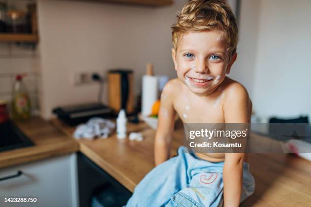 ragazzino carino seduto senza camicia sul bancone della cucina che guarda direttamente nella fotocamera - varicella foto e immagini stock