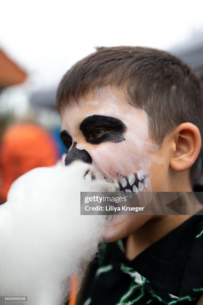 Young boy in Halloween costumes eats cotton candy.