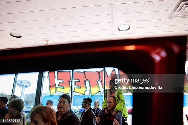 People listen to Republican presidential candidate, former House Speaker Newt Gingrich during a campaign event in the showroom of The Frederick Motor...