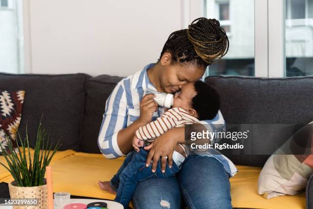 portrait of an african american woman feeding her baby boy at home - mother son milk imagens e fotografias de stock