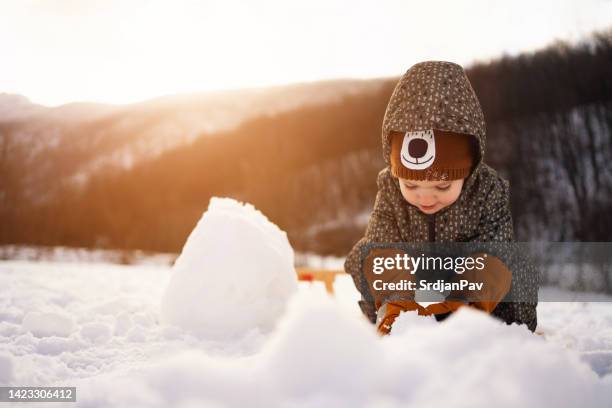 toddler boy making a snowman - kids playing snow stock pictures, royalty-free photos & images