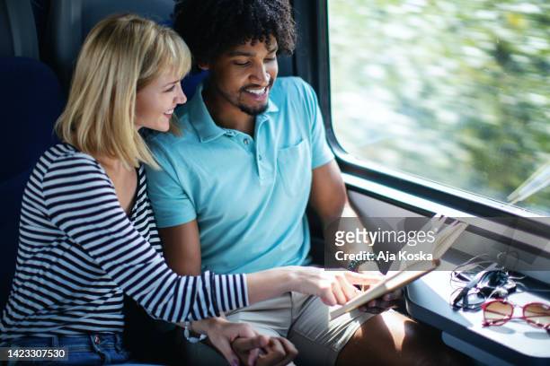 young couple traveling  by train. - woman blond looking left window stockfoto's en -beelden