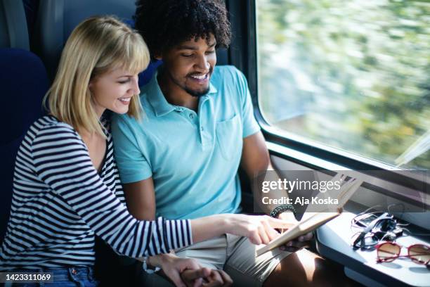 young couple traveling  by train. - woman blond looking left window stockfoto's en -beelden