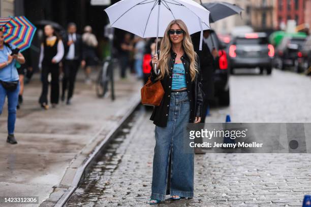 Emili Sindlev seen wearing black leather jacket, blue top, denim skirt with slit, brown wild leather bag outside Khaite during New York Fashion Week...