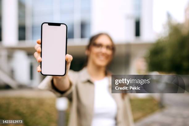 young woman holding isolated smartphone screen - tonen stockfoto's en -beelden