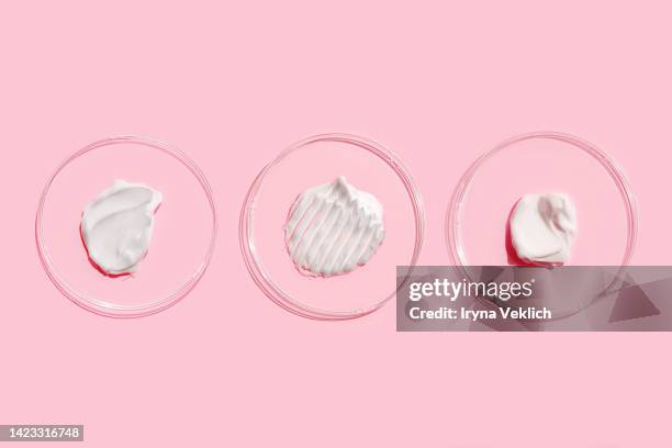 smears of beauty product white gel and cosmetic cream in petri dish on pastel pink color background. - hair treatment stock-fotos und bilder