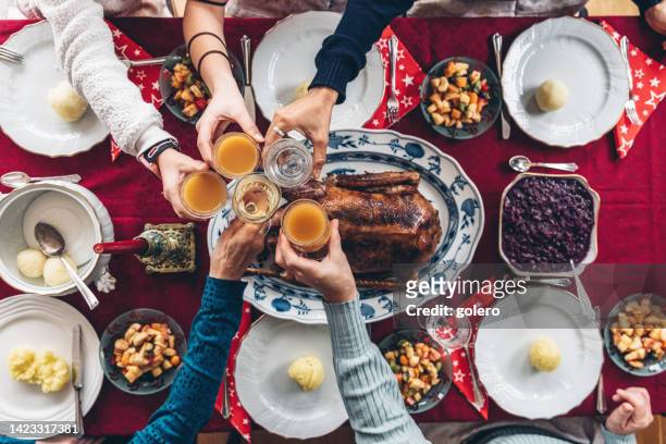family clinking glasses at festive christmas table - christmas background no people stock pictures, royalty-free photos & images