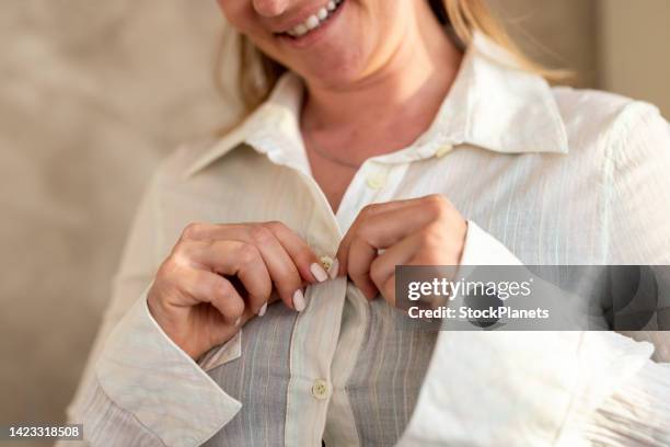 woman hands fastening button on shirt at home - knäppa knappar bildbanksfoton och bilder