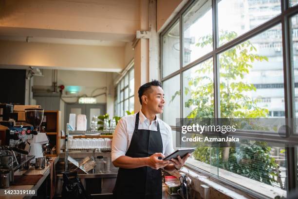 smiling chinese coffee bar owner looking out window - café bar 個照片及圖片檔